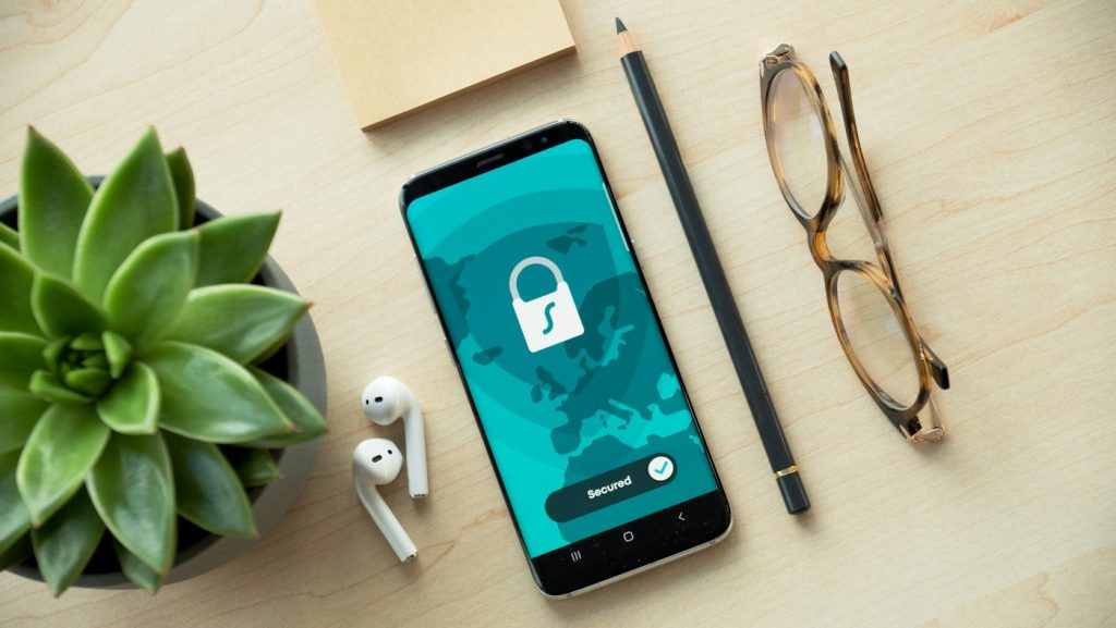 Ekranında kilit simgesi bulunan telefon, gözlük ve kalem