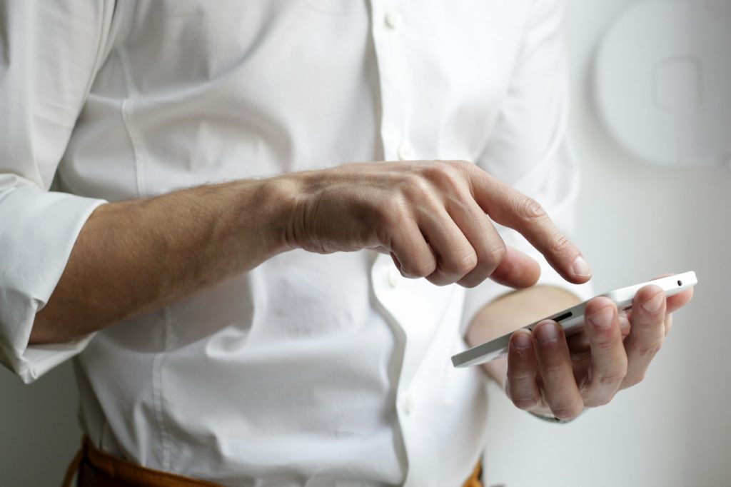 Elinde telefon tutan ve ekrana dokunan bir kişi