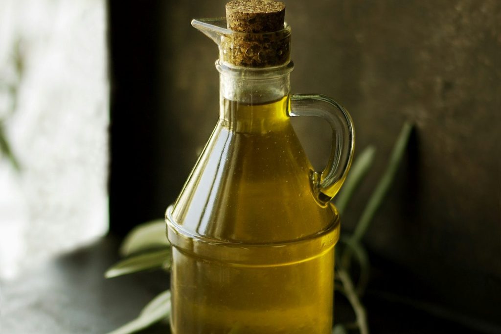 Zeytin dalı ve zeytinle yan yana duran zeytinyağı şişesi